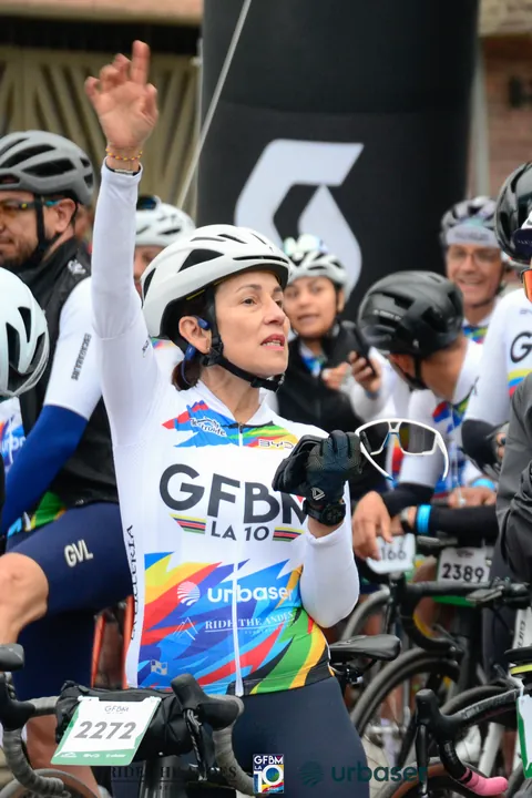 Una ciclista levanta la mano y sonríe entre el grupo de ciclistas de la salida