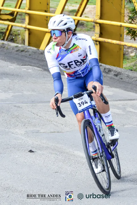 Un ciclista toma una curva junto a la baranda amarilla de un puente