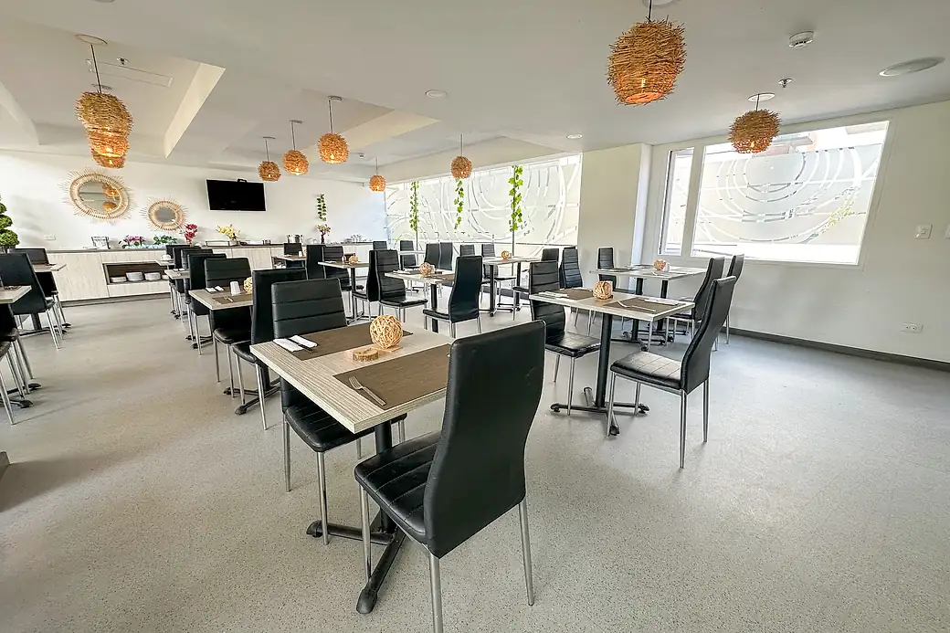 The breakfast room: square tables with placemats and black chairs, woven pendant lamps and the buffet counter at the back.