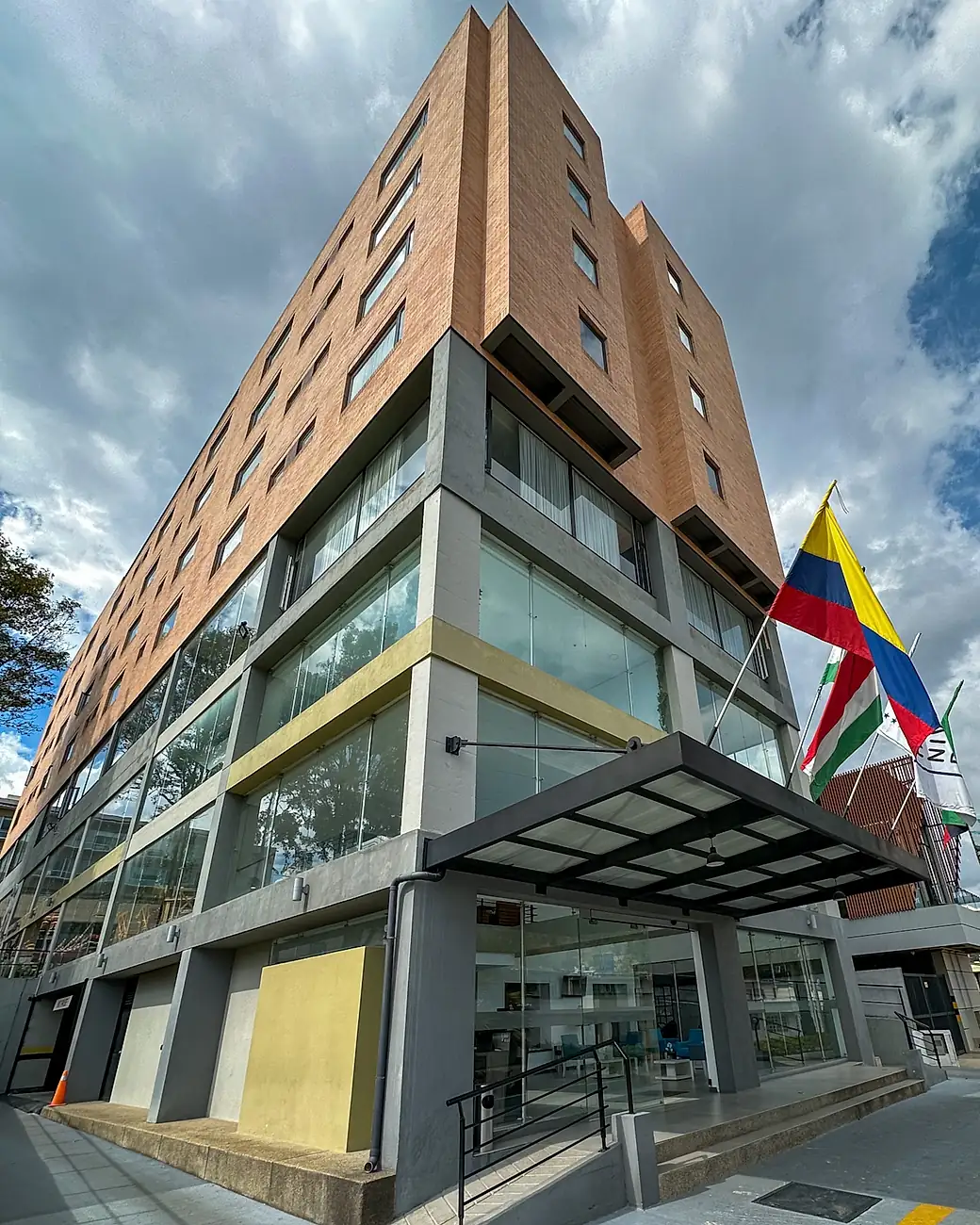 The front of Hotel Nivari Duitama: a brick tower over a glazed base, with the entrance canopy and the flags of Colombia and Boyacá.