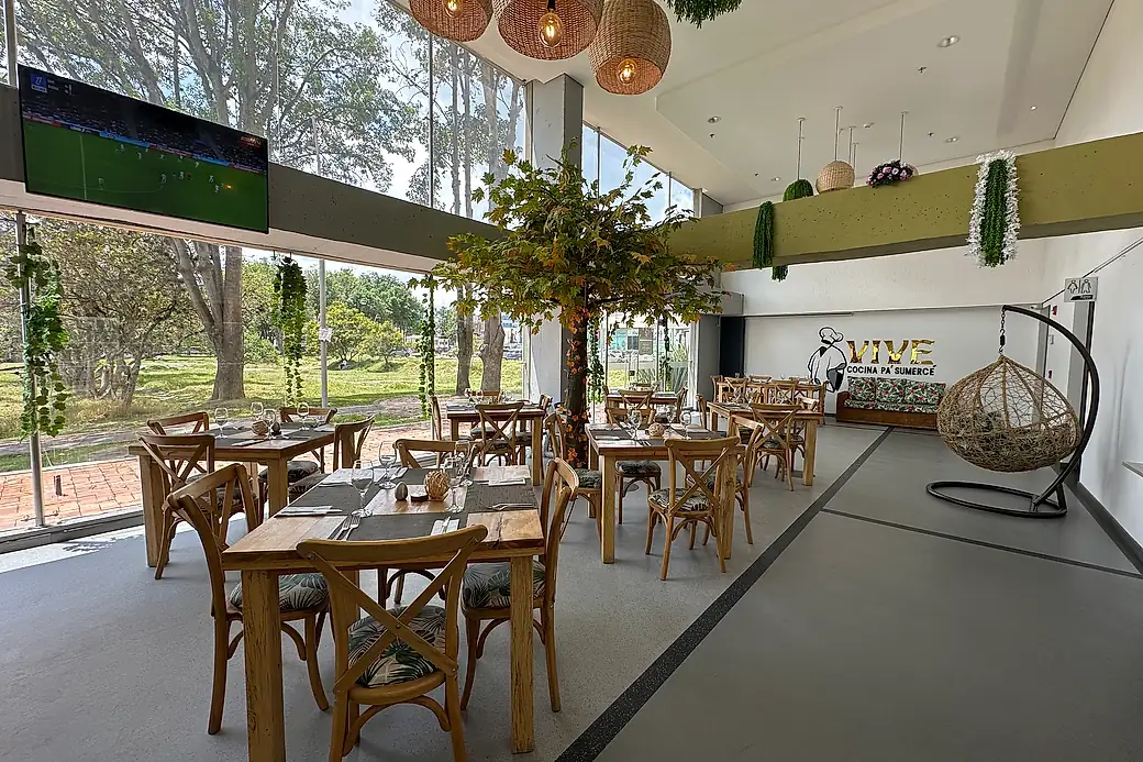 The hotel restaurant, with wooden tables beside a double-height window looking onto a wooded park.
