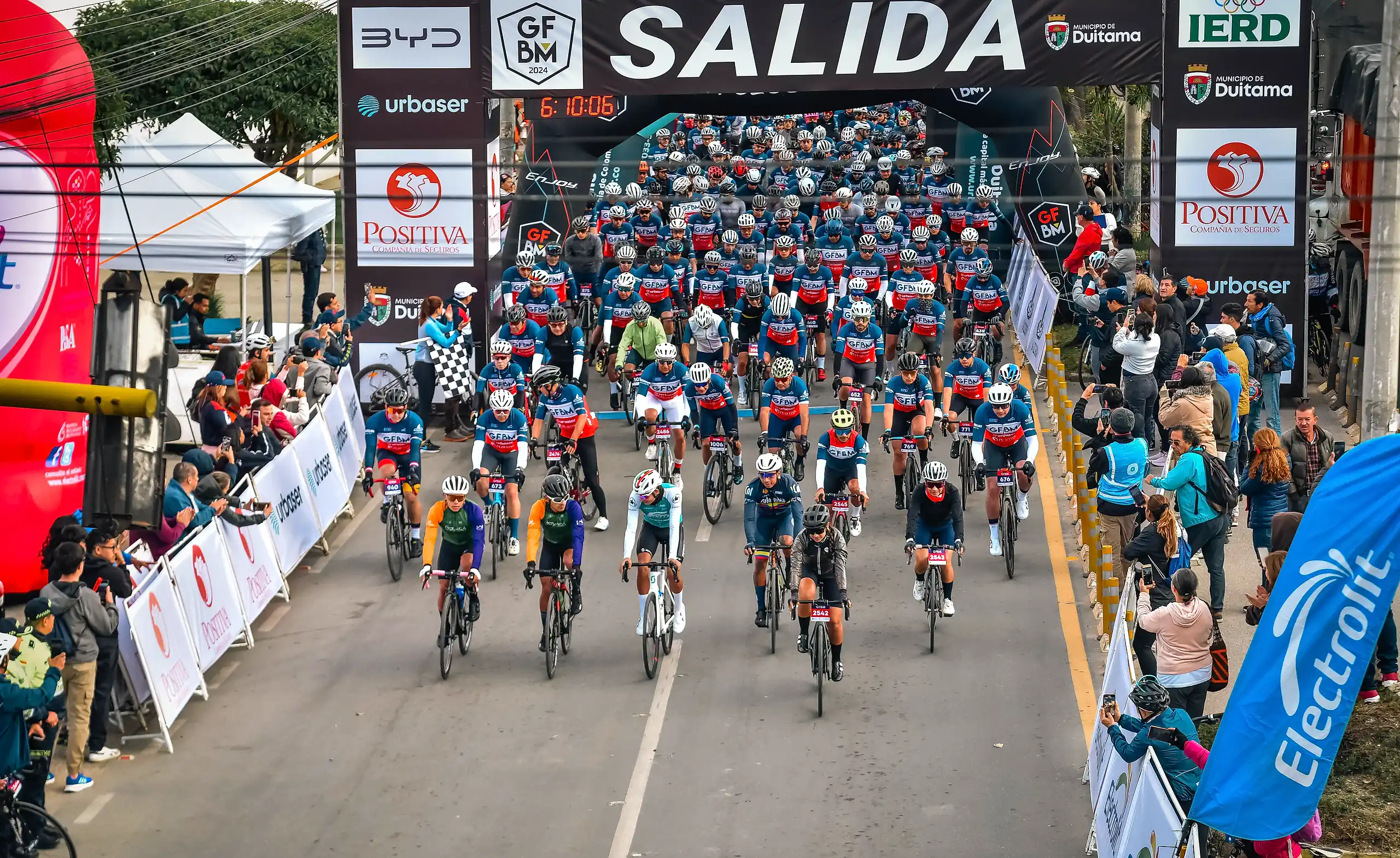Cientos de ciclistas arrancan bajo el arco de salida del Gran Fondo en Duitama, con público a los dos lados.