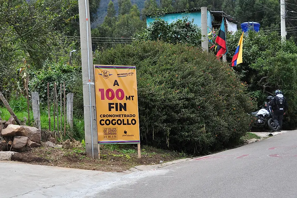 Valla al borde de la carretera que anuncia «A 100 metros, fin cronometrado Cogollo».