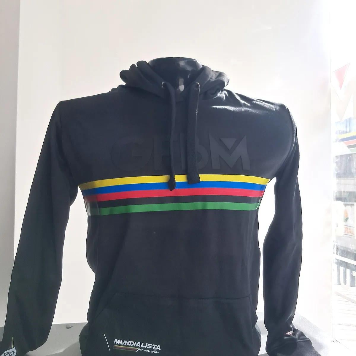 Black hooded sweatshirt of the 2025 edition, front view with drawstring and rainbow bands