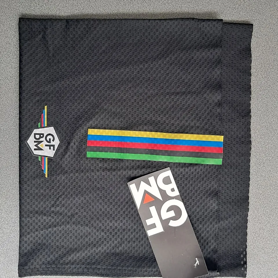 Black GFBM 2025 neck warmer laid flat: mesh fabric, GFBM crest and the rainbow stripes