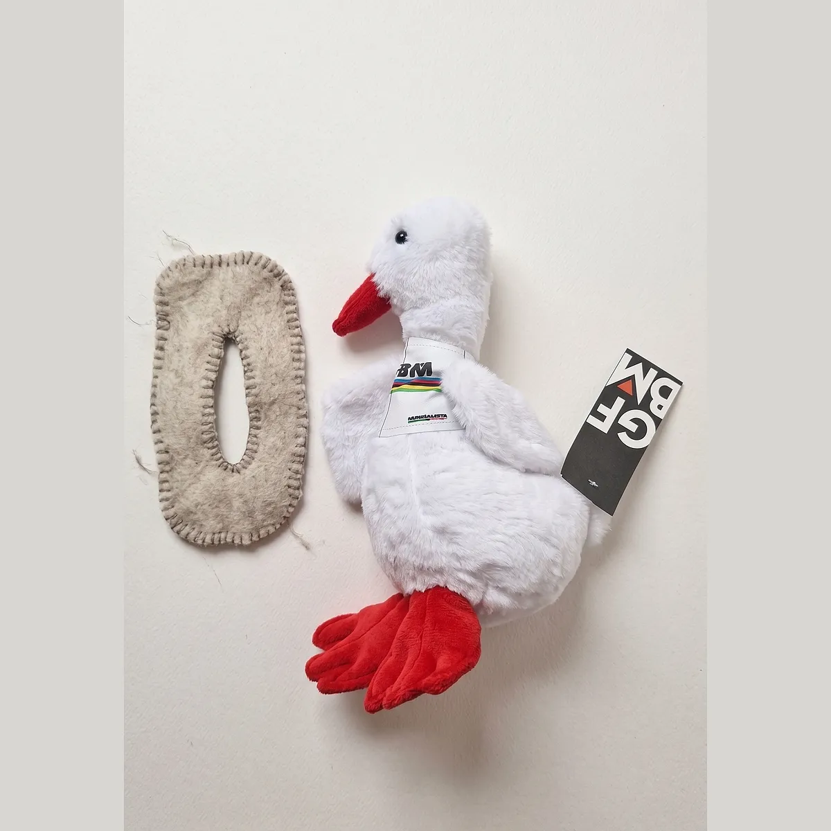 The Gran Fondo plush duck with its felt ruana laid loose beside it